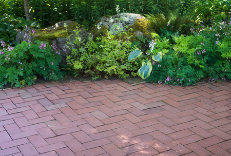 A natural shade perennial garden borders a brick patio