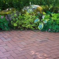 a natural shade perennial garden borders a brick patio Power Washing in Naples, FL